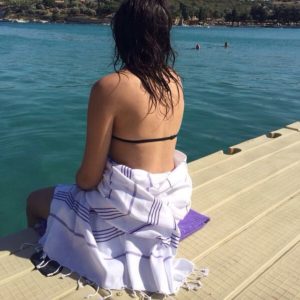 A woman sitting on microfiber towel and wrapped in turkish towel