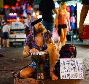 A backpacker begging for money in thailand with a musical instrument