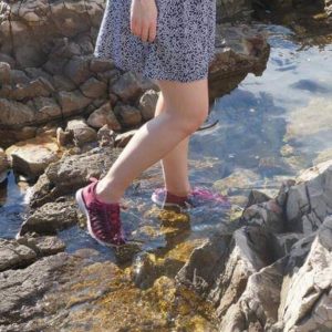 legs of woman walking on water and wearing keen uneek travel sandals