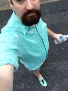 A man wearing linen shirt and holding water bottle in one hand