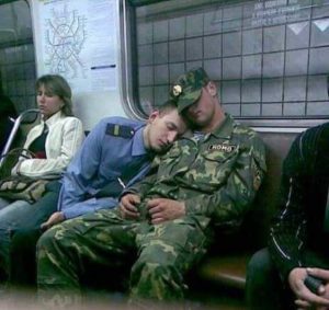 Two soldiers sleeping on each other shoulder during flight