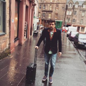 A man wearing a blazer and carrying luggage