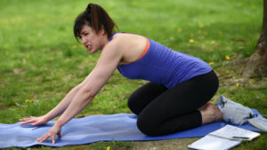 Woman doing yoga on a yoga mat in a park