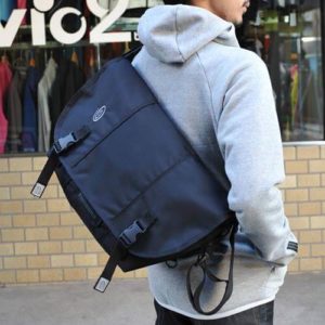 man carrying timbuk2 classic messenger bag infront of a clothing store