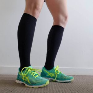 legs of woman wearing compression socks with running shoes