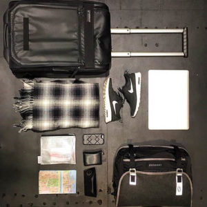 A well organized suitcase with packed items lying beside it