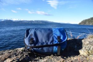 A blue Timbuk2 classic messenger bag in front of a lake