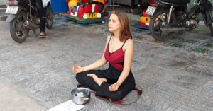 western Woman begging for money in vietnam doing yoga