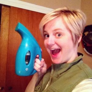 a lady holding blue color portable steamer and very excited