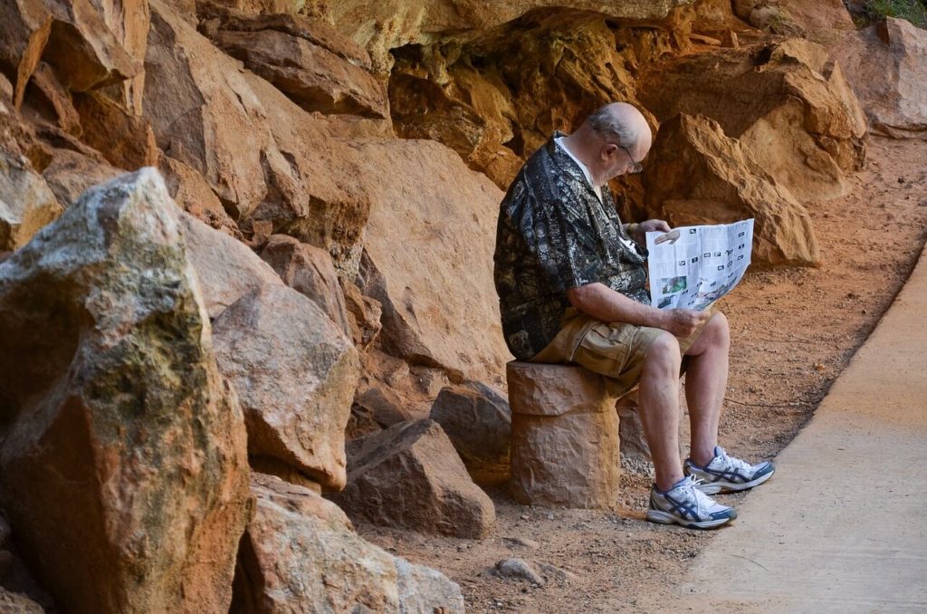 old man reading a map at a tourist site