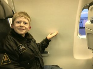 Boy pointing to space without window in a flight