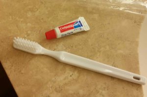 Travel sized toothpaste against a toothbrush